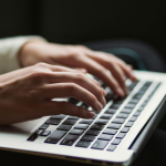A person typing on the keyboard of a laptop.