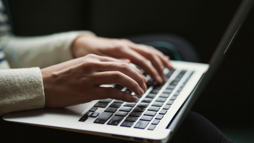 A person typing on the keyboard of a laptop.