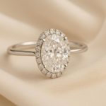 Oval engagement ring with sparkling diamond set in elegant band on soft neutral background