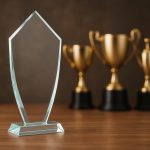 Clear glass award trophy displayed on a desk, symbolizing modern business recognition preferences