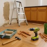 Kitchen with unfinished cabinets, exposed wiring, and paint cans showing renovation mistakes
