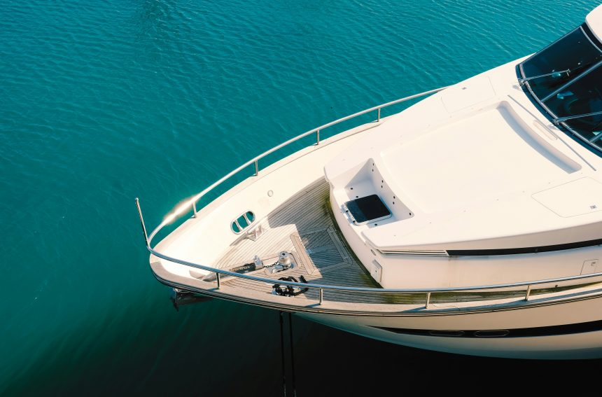 Modern boat with glossy hull showing durable marine coating, docked in clear blue water.