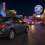 Damaged car on Las Vegas street after hit-and-run accident, flashing police lights nearby