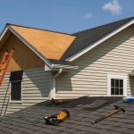 Workers installing new shingles and underlayment on a residential home during roof replacement