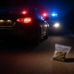 Police car with flashing lights stopped on roadside during traffic enforcement for drug investigation