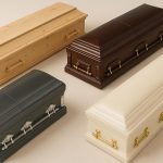 Various casket styles displayed side by side in a funeral showroom setting
